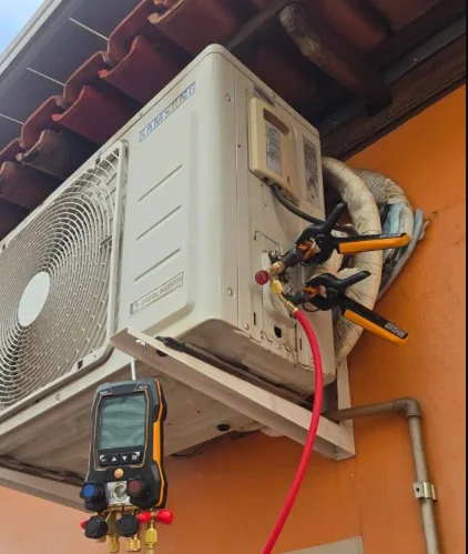 Condensadora de ar-condicionado instalada na parede, com manifold digital conectado para medir a pressão